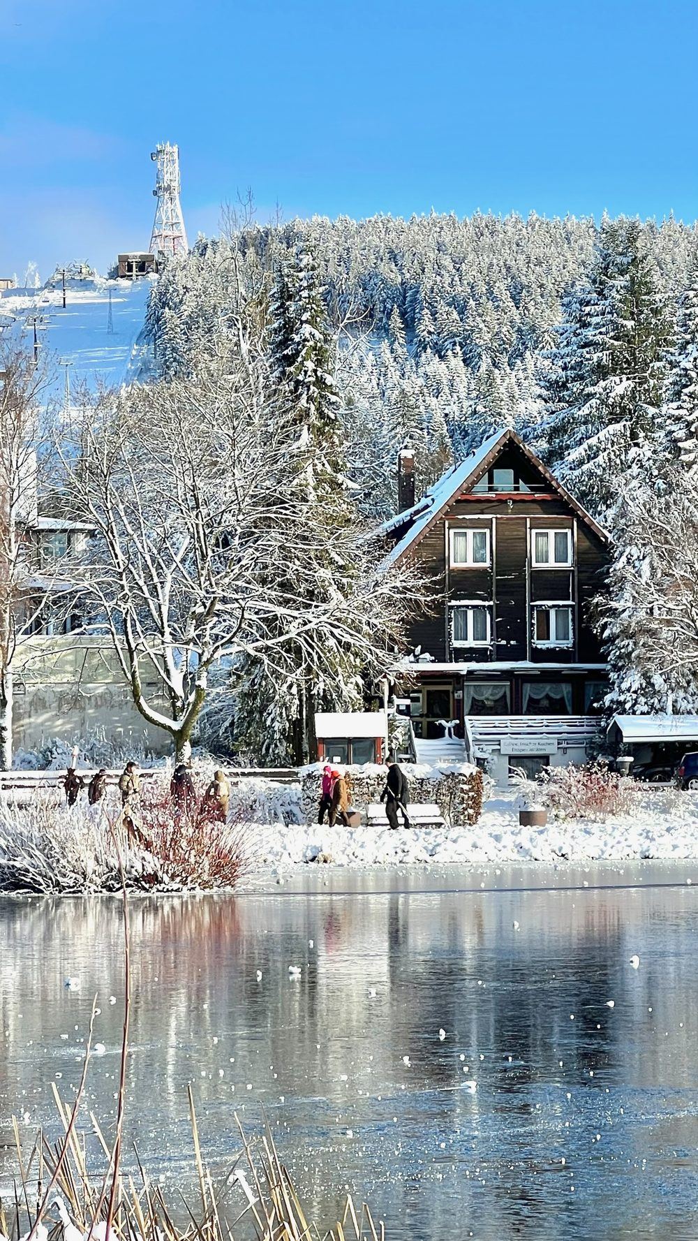 Winterblick über den See zur Lodge, Bocksberg mit Skigebiet im Hintergrund · Winter lake view with Bocksberg ski area
